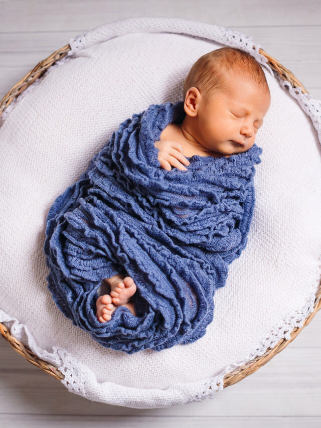 newborn-baby-enveloped-blue-scarf-sleeps-white-pillow